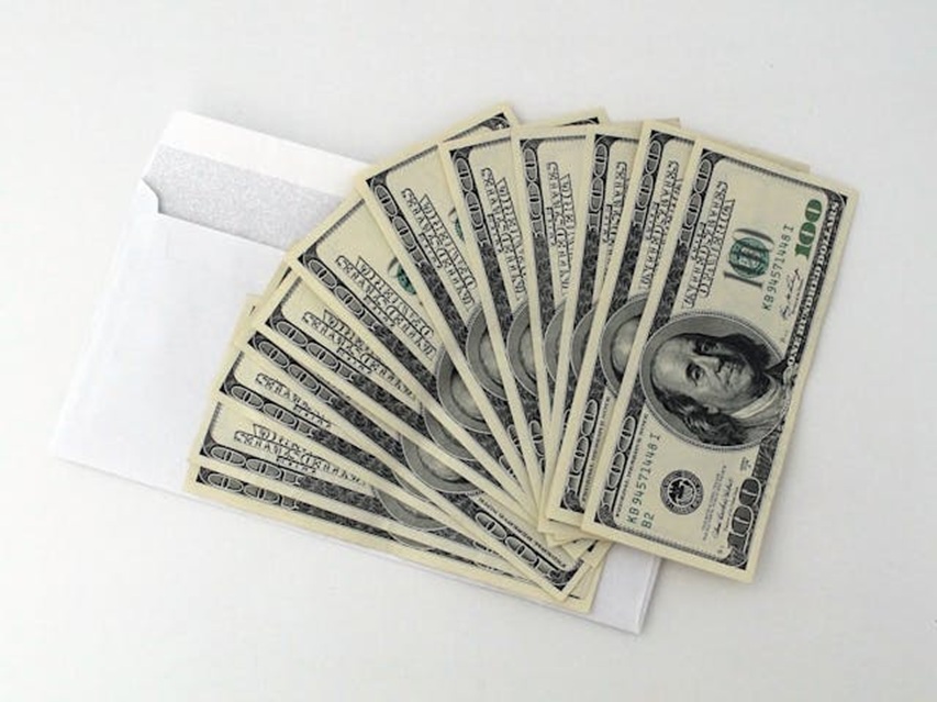 an envelope with a fanned out stack of cash on top